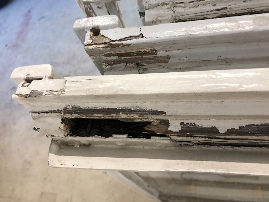 Nahaufnahme von morschen und beschädigten Holzfensterrahmen vor der Sanierung.